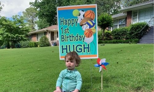 cute baby in yard with first birthday yard sign