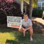 high school senior Sullivan in yard with graduation signs